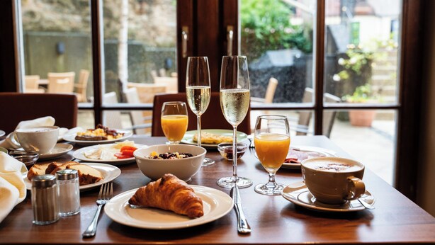 Una mesa de desayuno con cruasanes, zumo de naranja y copas de champán.