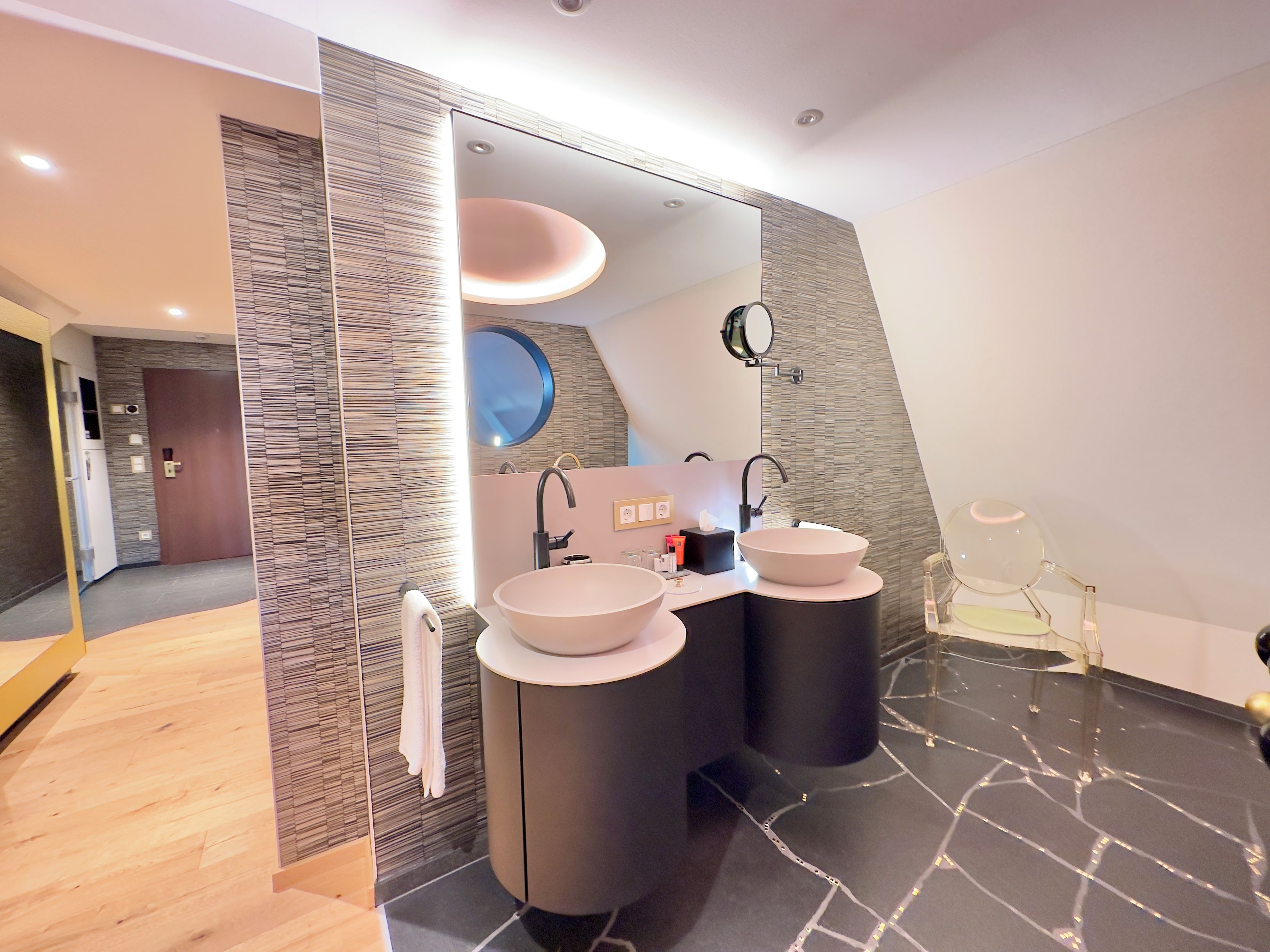 Ein modernes Badezimmer mit zwei Waschbecken, einem großen Spiegel und einem Waschtisch mit einem runden Spiegel.