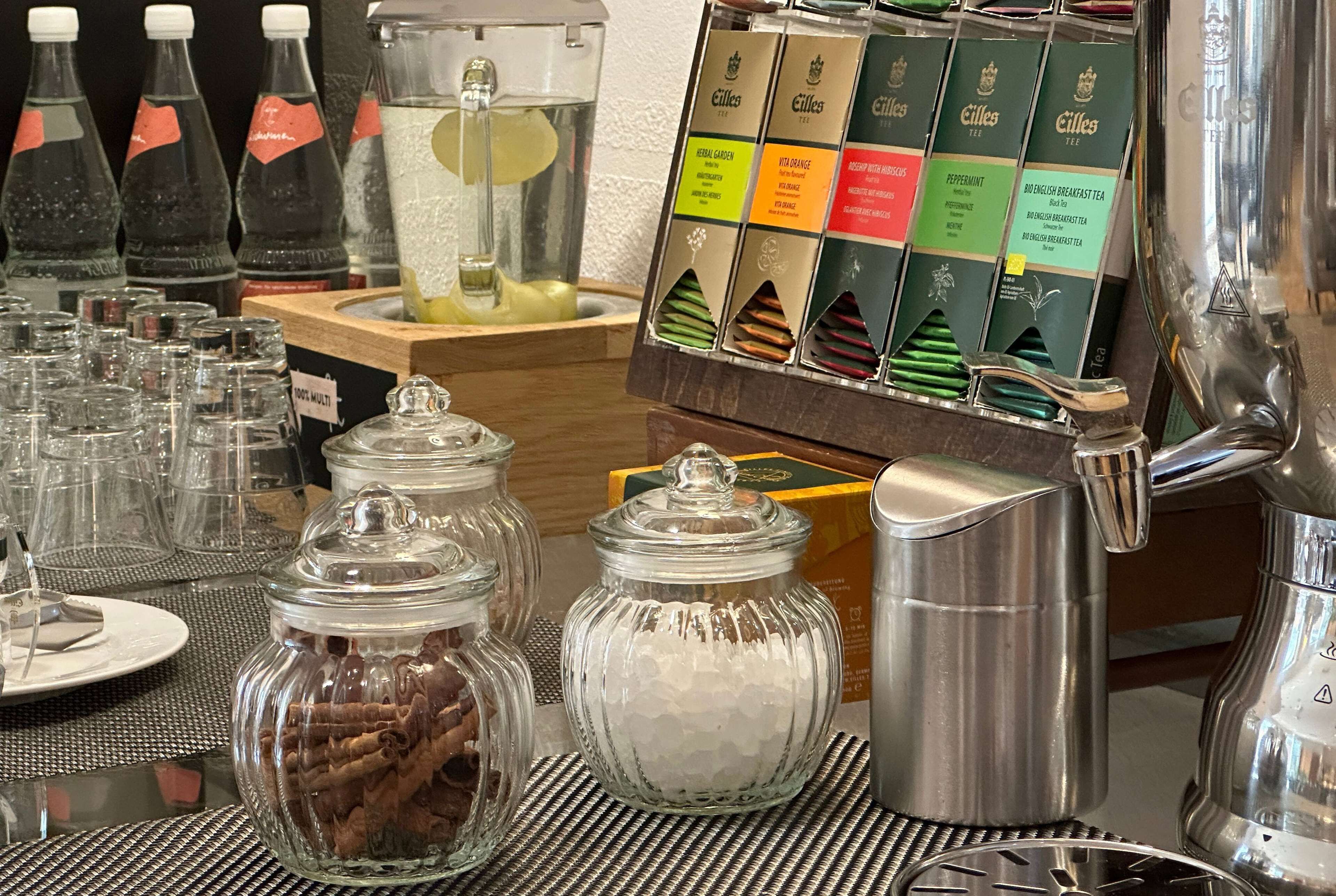 Una estación de café con diversas opciones de té y café, incluyendo una selección de tés y una cafetera.