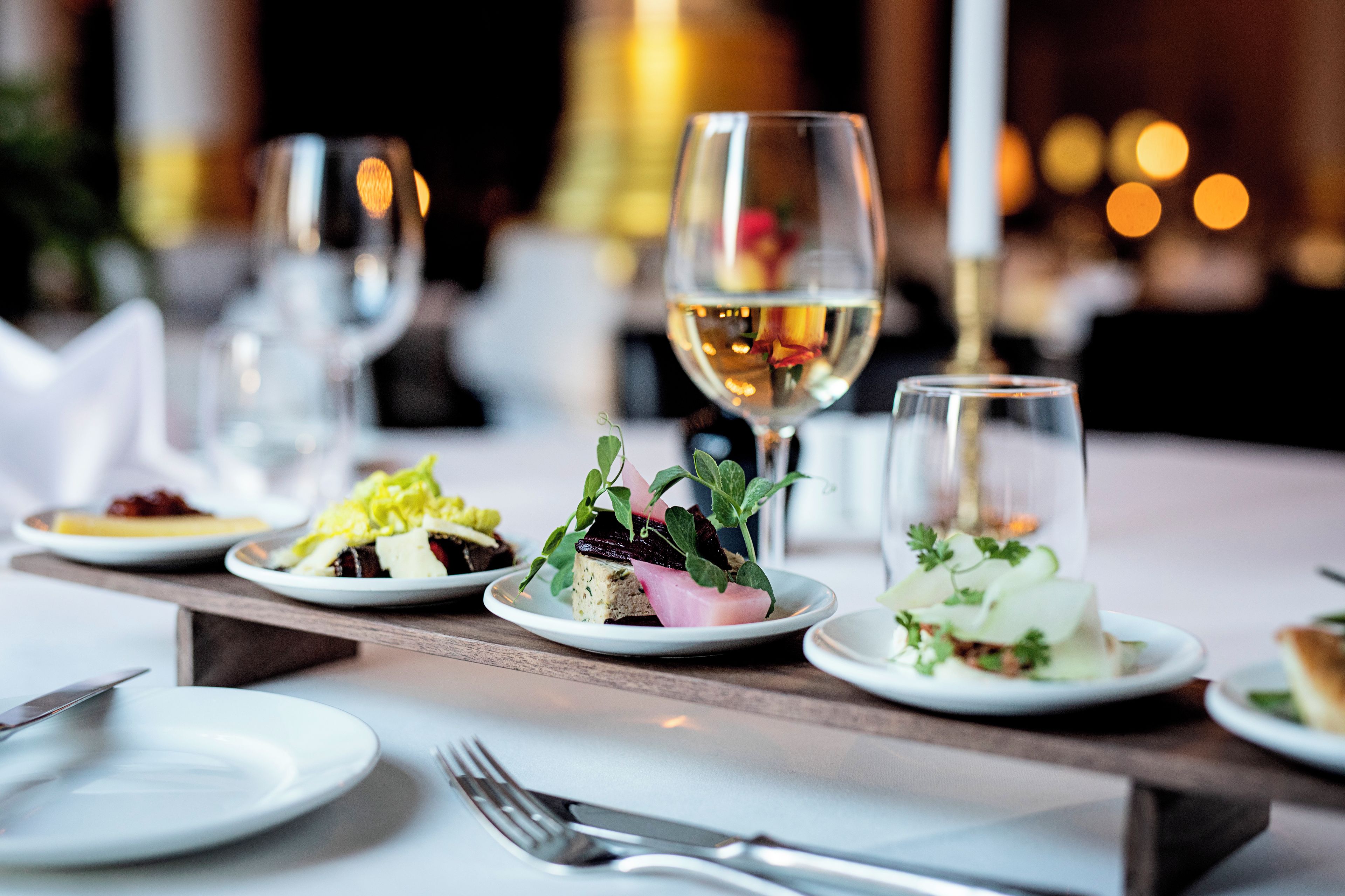 A dining table with plates of food, glasses of wine, and cutlery.