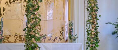 A room with a floral archway, a table with a white cloth, and a chandelier.