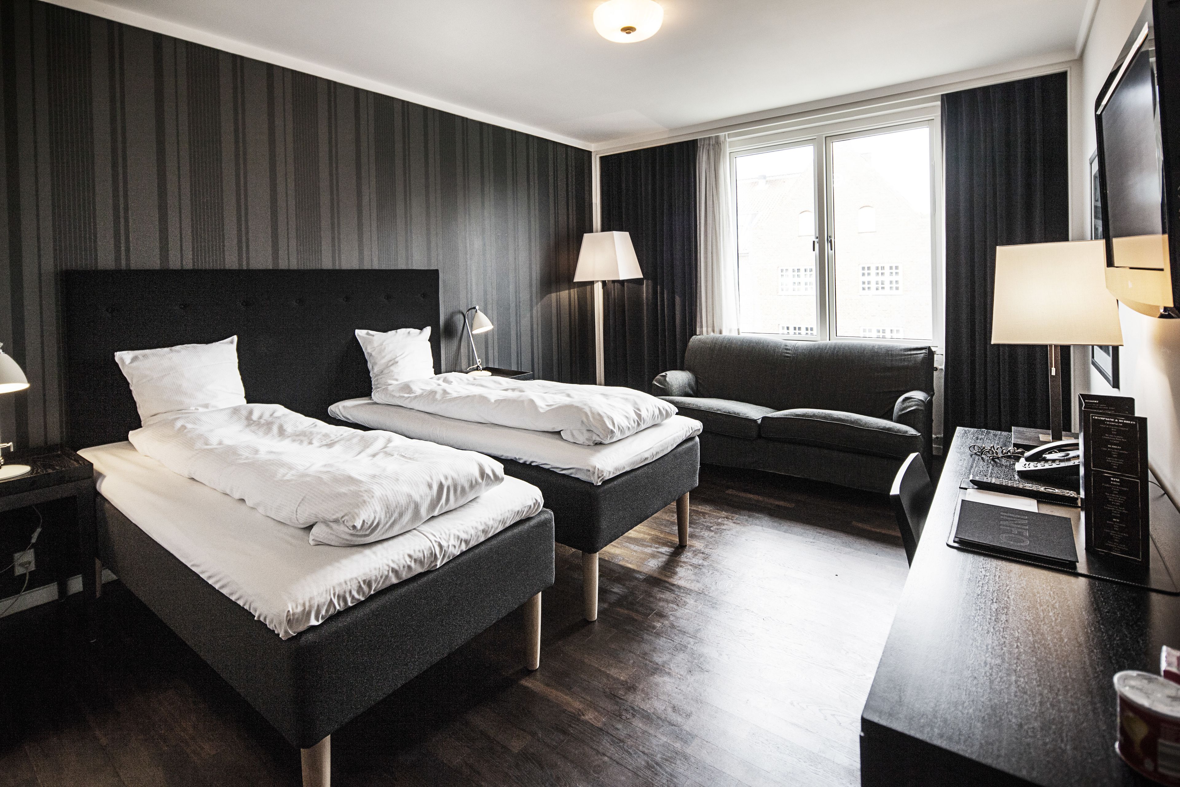 Habitación de hotel con dos camas, un escritorio, una silla y un televisor.