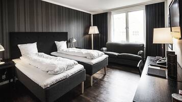 Habitación de hotel con dos camas, un escritorio, una silla y un televisor.