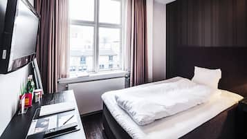 Una habitación de hotel con una cama, un escritorio con ordenador, televisión y ventana con cortinas.