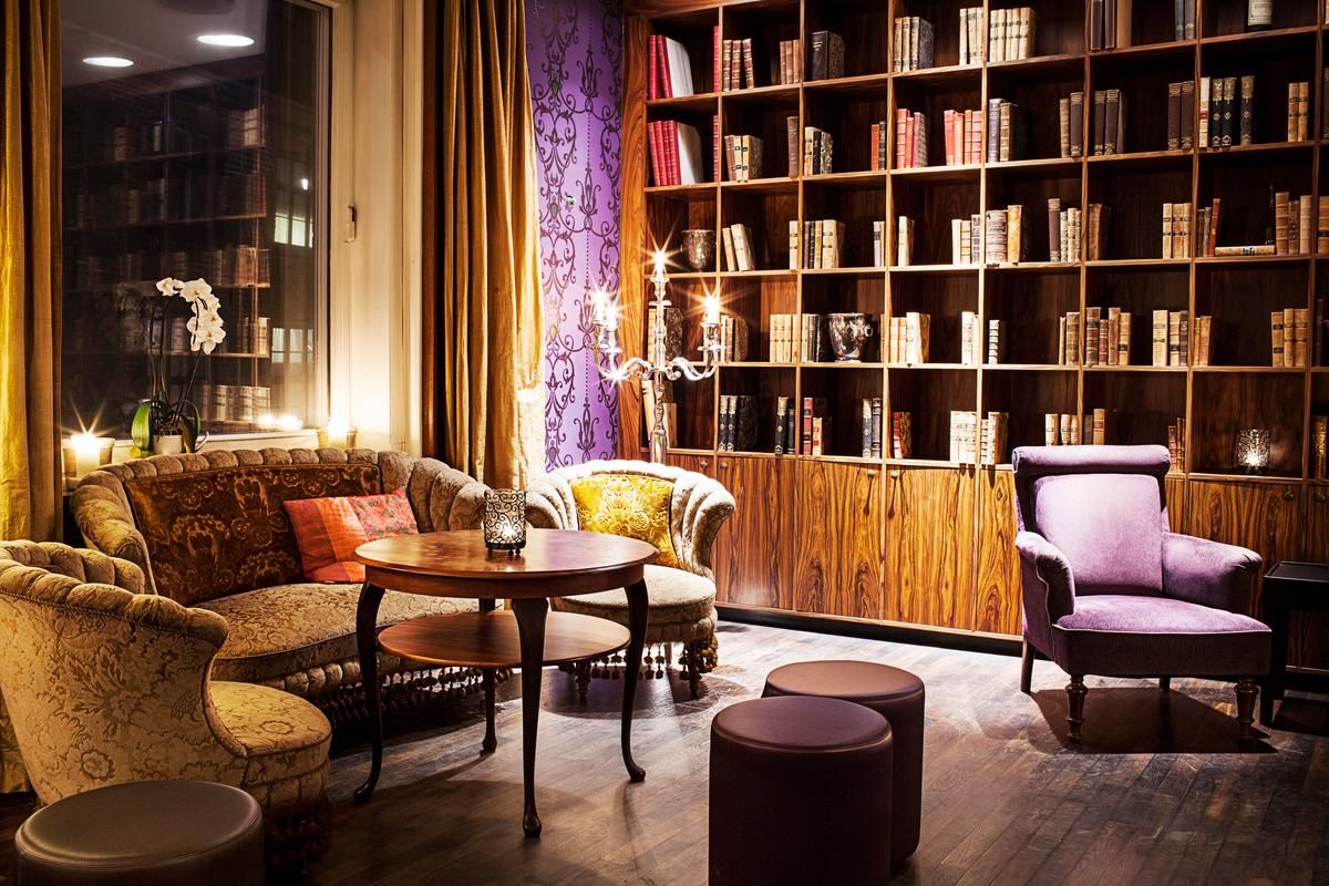 Un salón de lectura acogedor con una amplia estantería de madera, asientos cómodos y un jarrón decorativo.