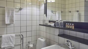 A bathroom with white tiles, a sink, a mirror, and a towel rack.