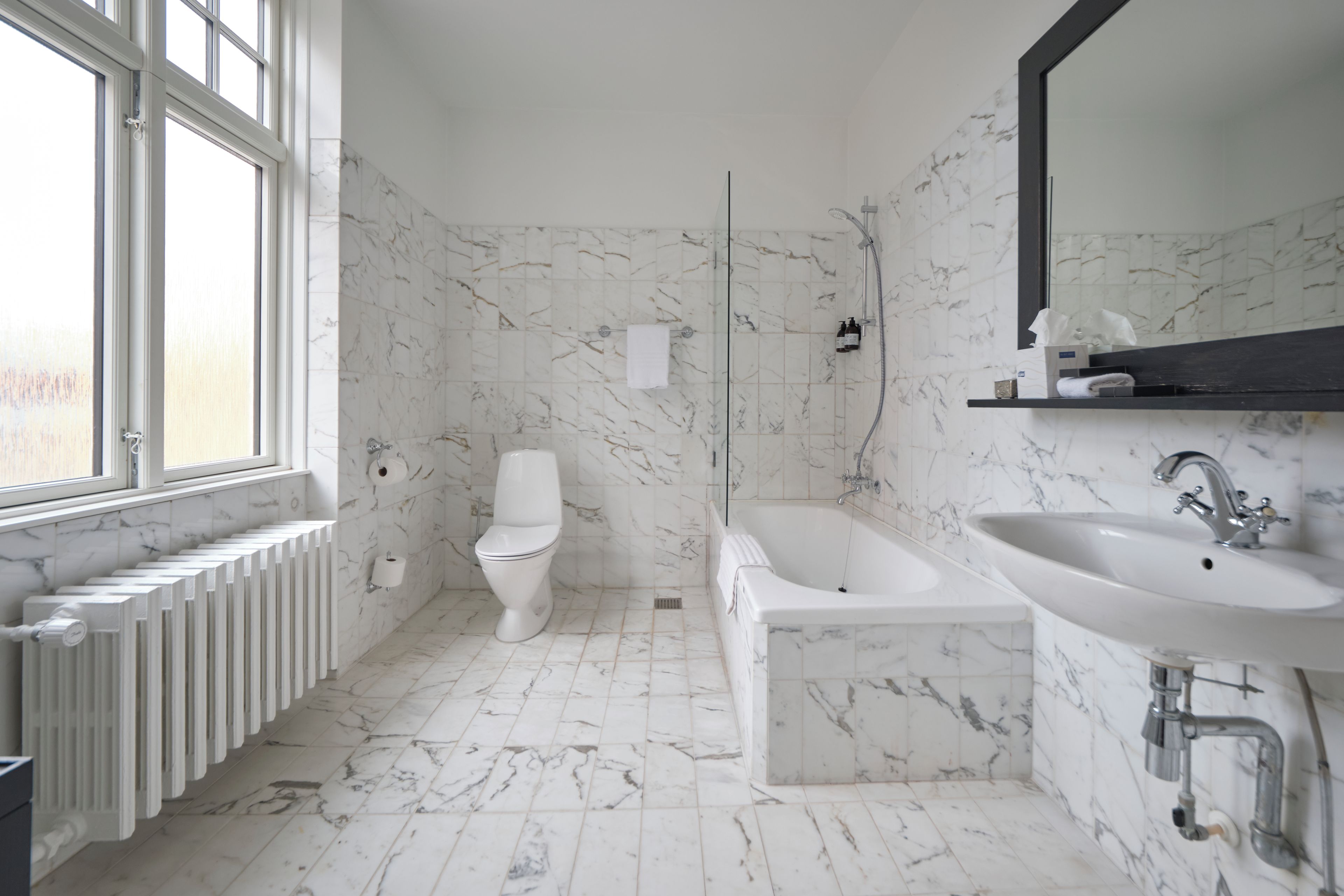A bathroom with a bathtub, a sink, a toilet, and a window.