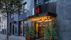 A modern building with a prominent RED sign, large potted plants, and a well-lit entrance.