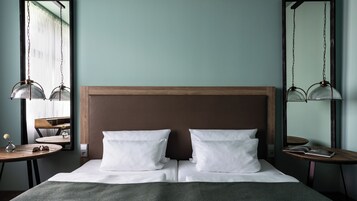 A neatly made bed with white linens, a wooden headboard, and two bedside tables with lamps.