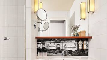 Un baño moderno con un lavabo blanco, dos espejos adosados a la pared y un estante con artículos de aseo.
