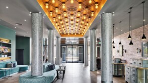Un vestíbulo espacioso con diseño moderno, que cuenta con una zona de estar central, un mostrador de recepción e iluminación expuesta en el techo.
