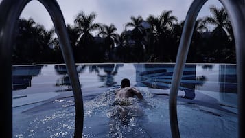 Una piscina al aire libre, sombrillas, sillones reclinables de piscina