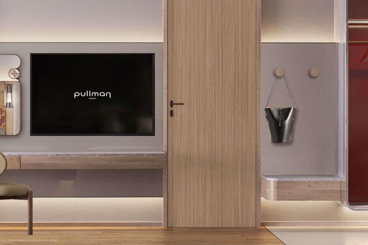 A modern interior with a flat-screen TV mounted on a wall, a wooden wardrobe, and a small metal bucket hanging on the wall.