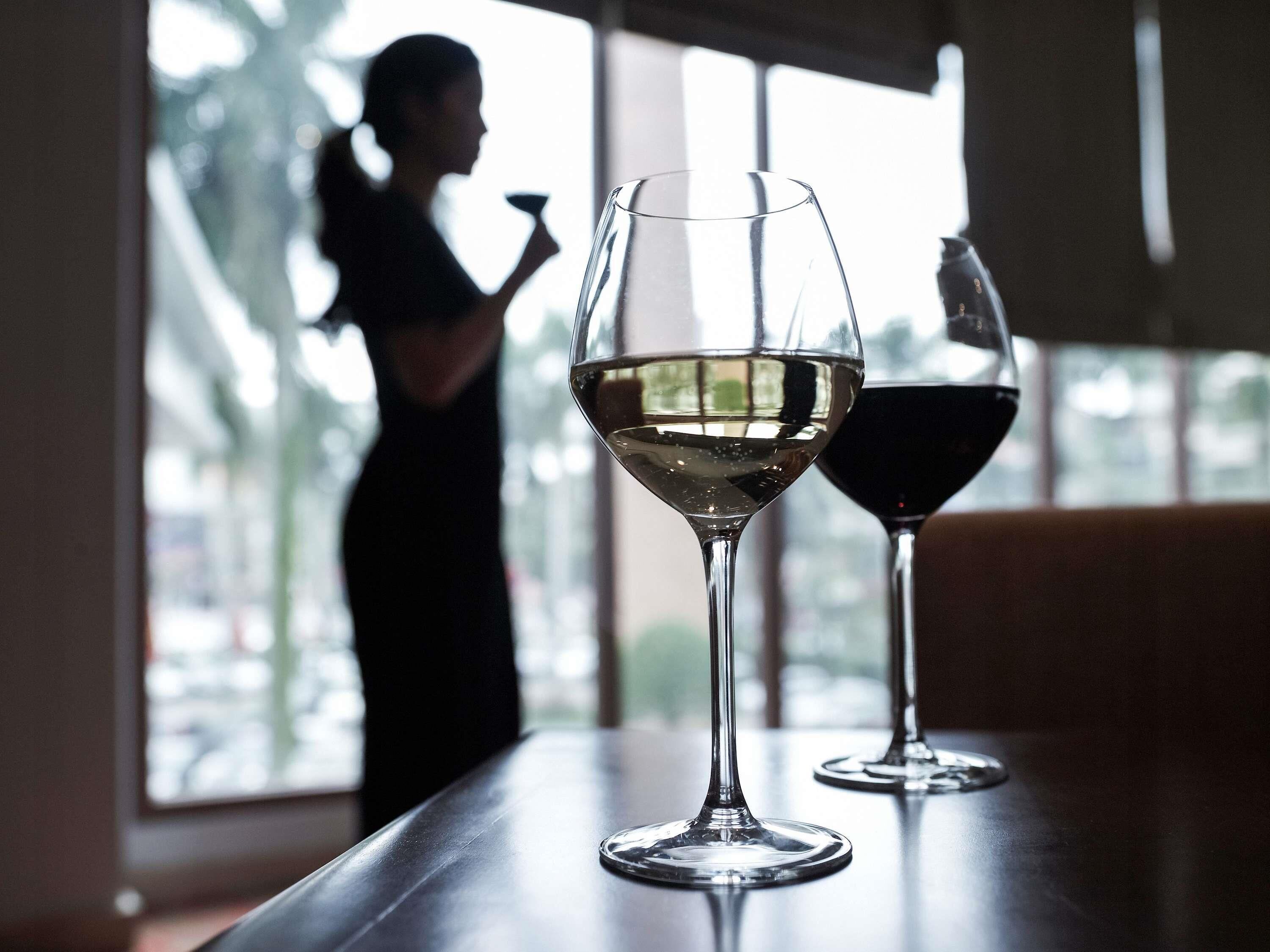 Two wine glasses on a table with a person in the background.