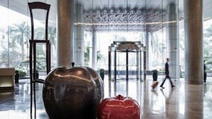 Un vestíbulo amplio con una gran escultura esférica oscura y un objeto rojo con forma de corazón.