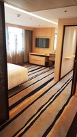 Una habitación de hotel con una cama, un televisor en la pared, un escritorio y una puerta.