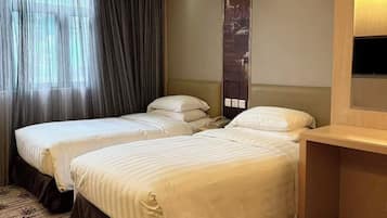 A hotel room with two beds, a large window with curtains, a cityscape view, and a wooden nightstand.