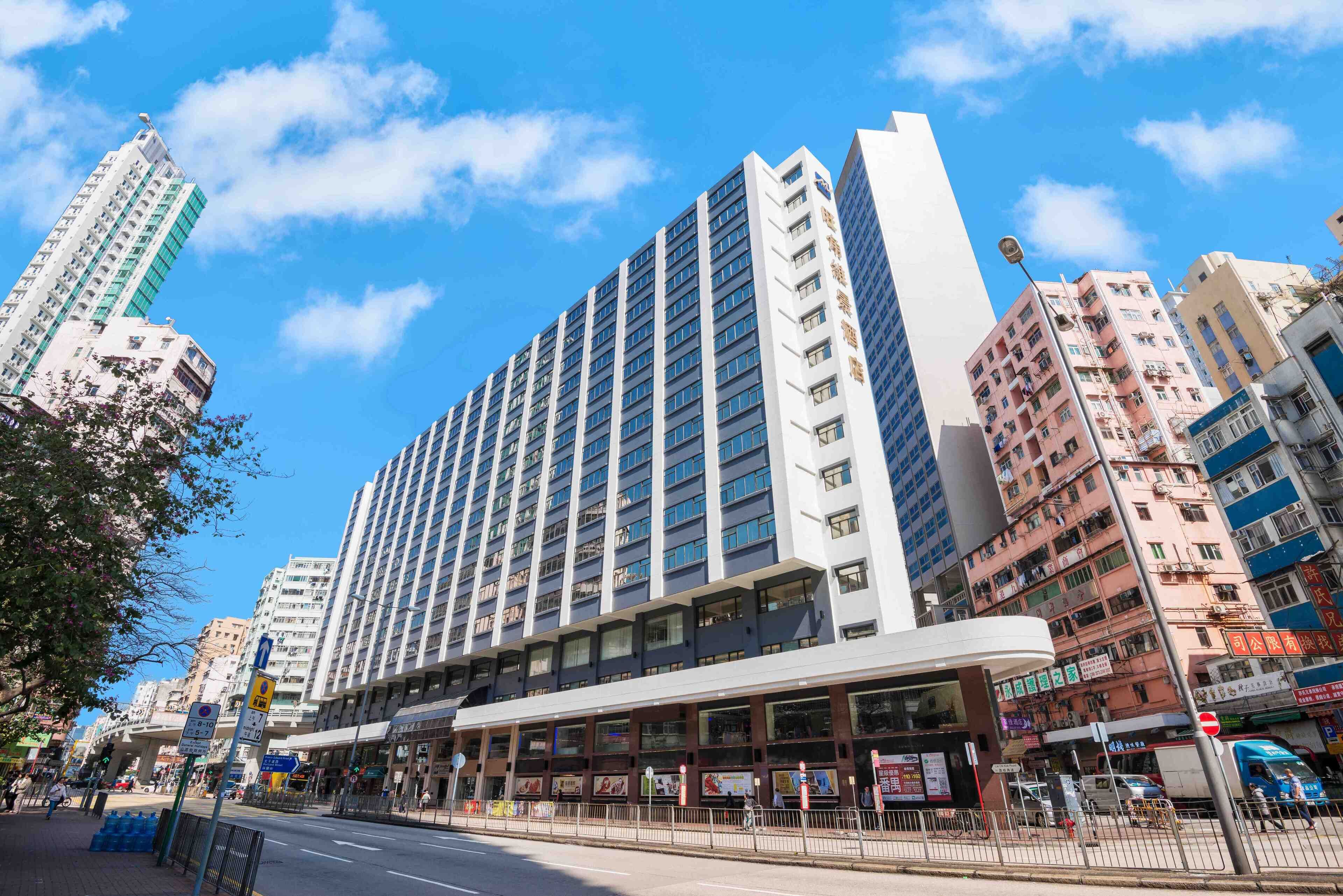 A modern hotel with multiple floors, large windows, and a covered entrance area.