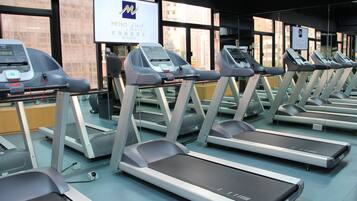 A row of treadmills in a gym with a sign for Metro Park Hotel in the background.