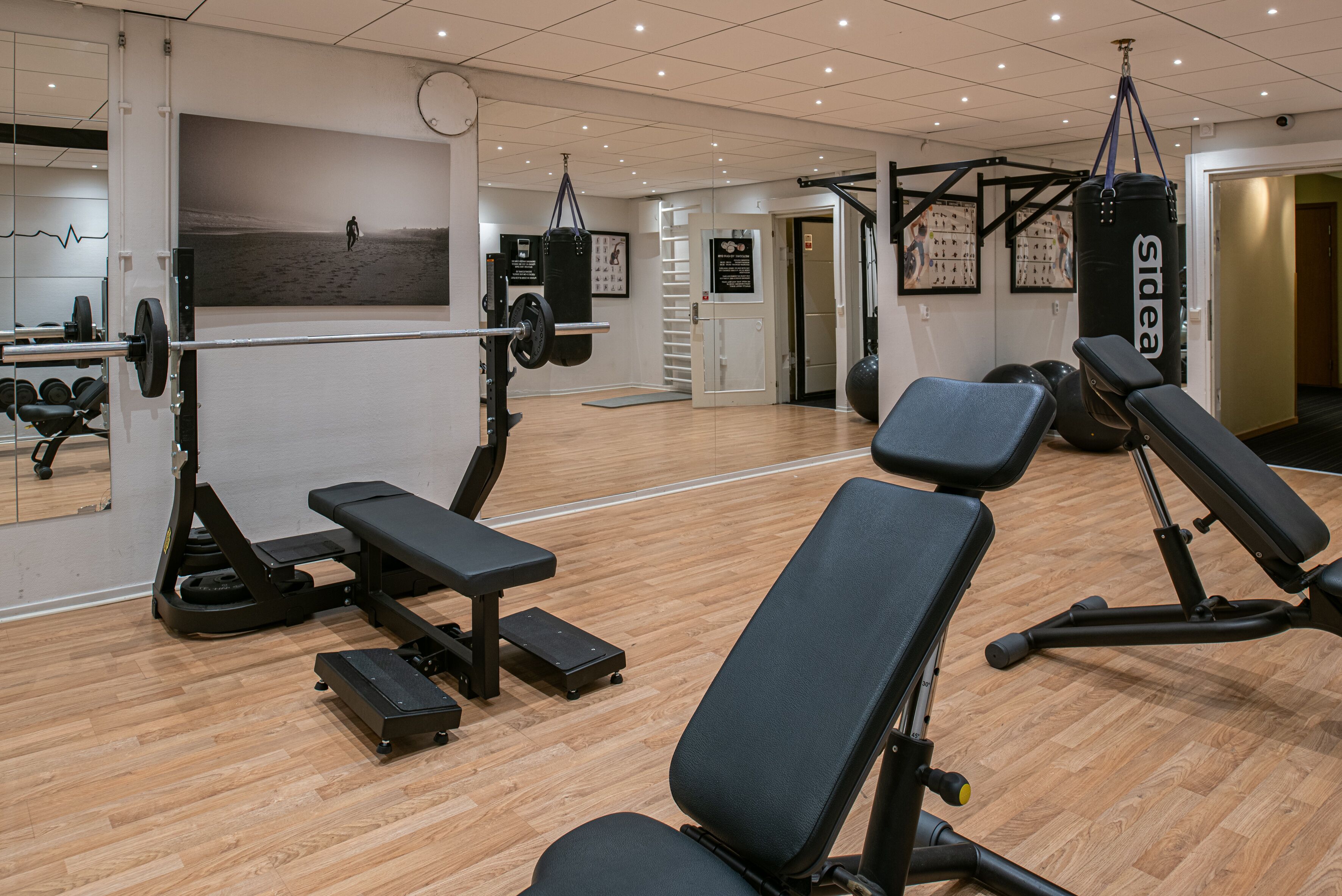 A gym with exercise equipment, a mirror, and a wooden floor.