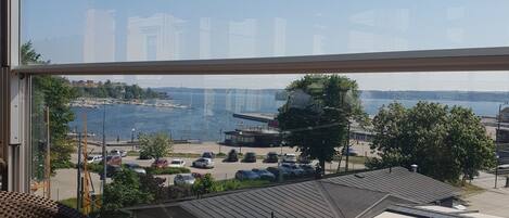 A view from a window overlooking a marina with boats, a parking lot, and buildings in the distance.