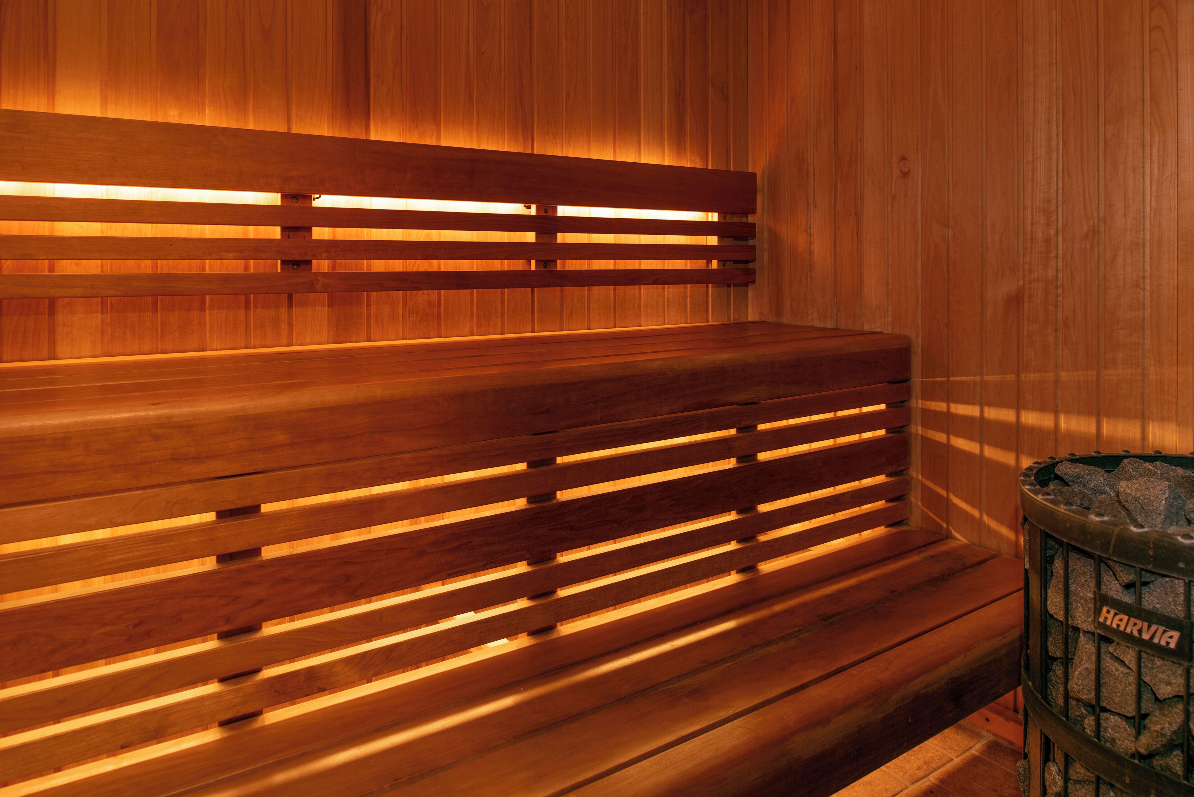 A wooden sauna bench with slats and a stone container labeled "HARVIA" on the right.
