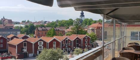 A balcony with a view of a town, featuring red brick buildings and a church tower.
