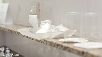 A bathroom counter with toiletries including a bottle, a packet, and two glasses.