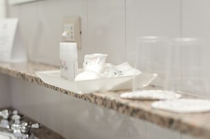A bathroom counter with toiletries including a bottle, a packet, and two glasses.