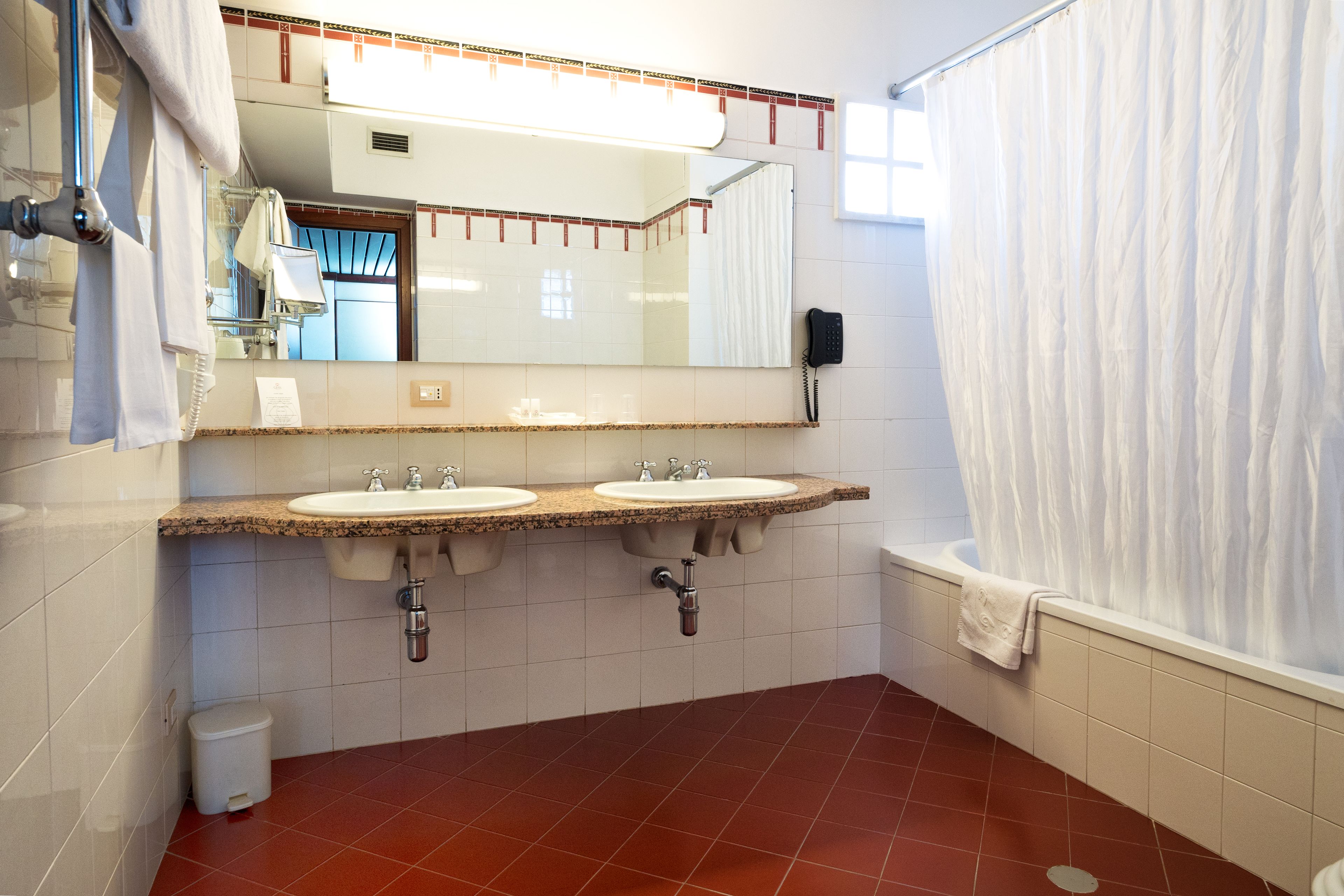 Een badkamer met twee wasbakken, een spiegel, een douchegordijn en een telefoon.