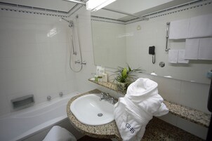 A bathroom with a white bathtub, a granite countertop sink, a mirror, and a towel rack.