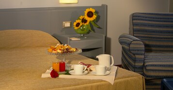 Una mesa de desayuno ordenada con una bandeja de frutas, dos tazas, una jarra y un florero con girasoles.