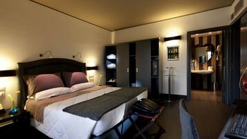 Une chambre d’hôtel moderne, avec un lit soigneusement fait, un bureau avec un ordinateur et une salle de bain visible à travers une porte ouverte.