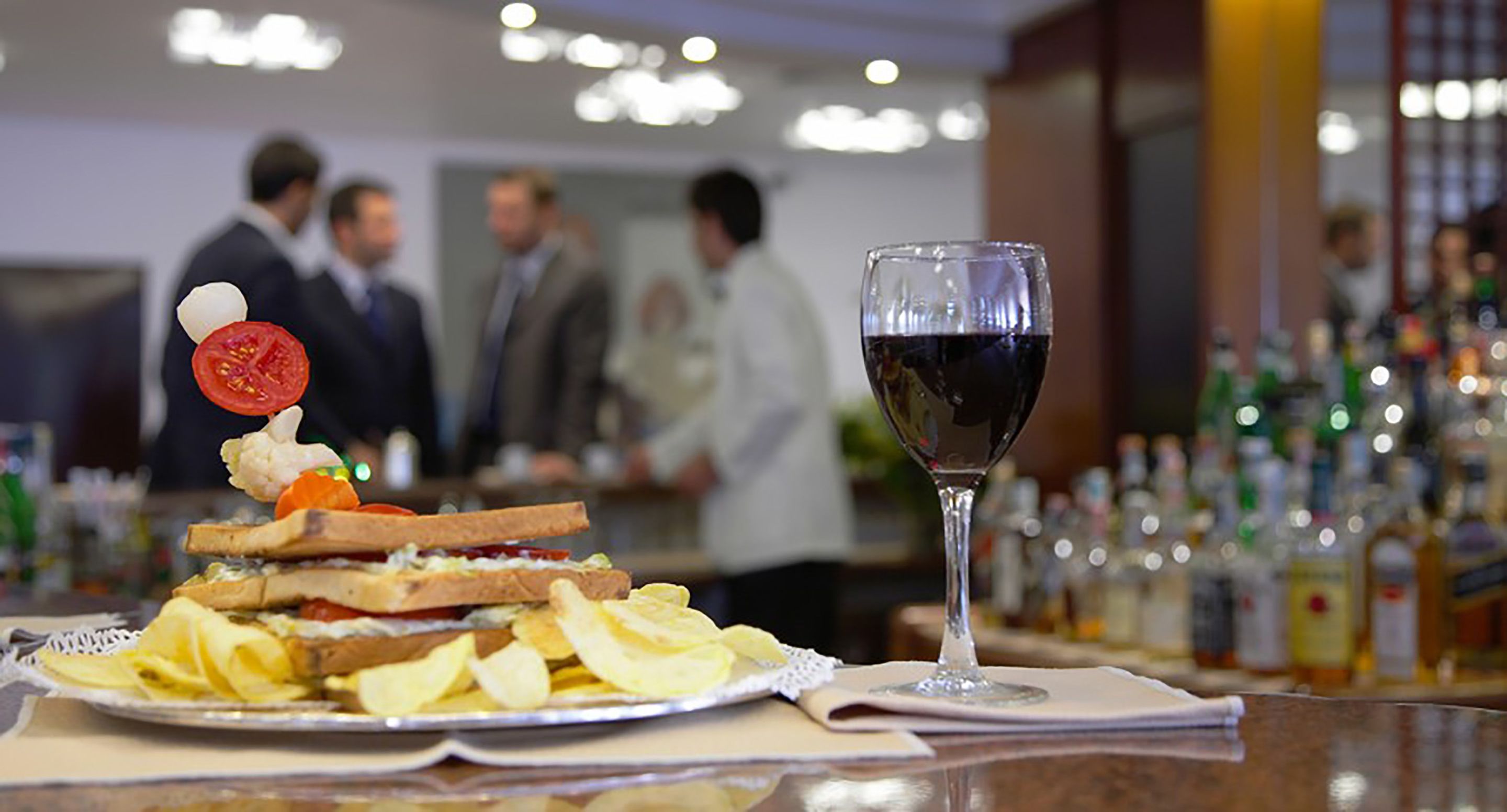Eine Bar mit Sandwich, Pommes und einem Weinglas.