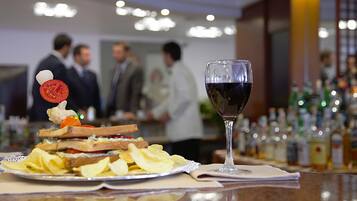 Eine Bar mit Sandwich, Pommes und einem Weinglas.