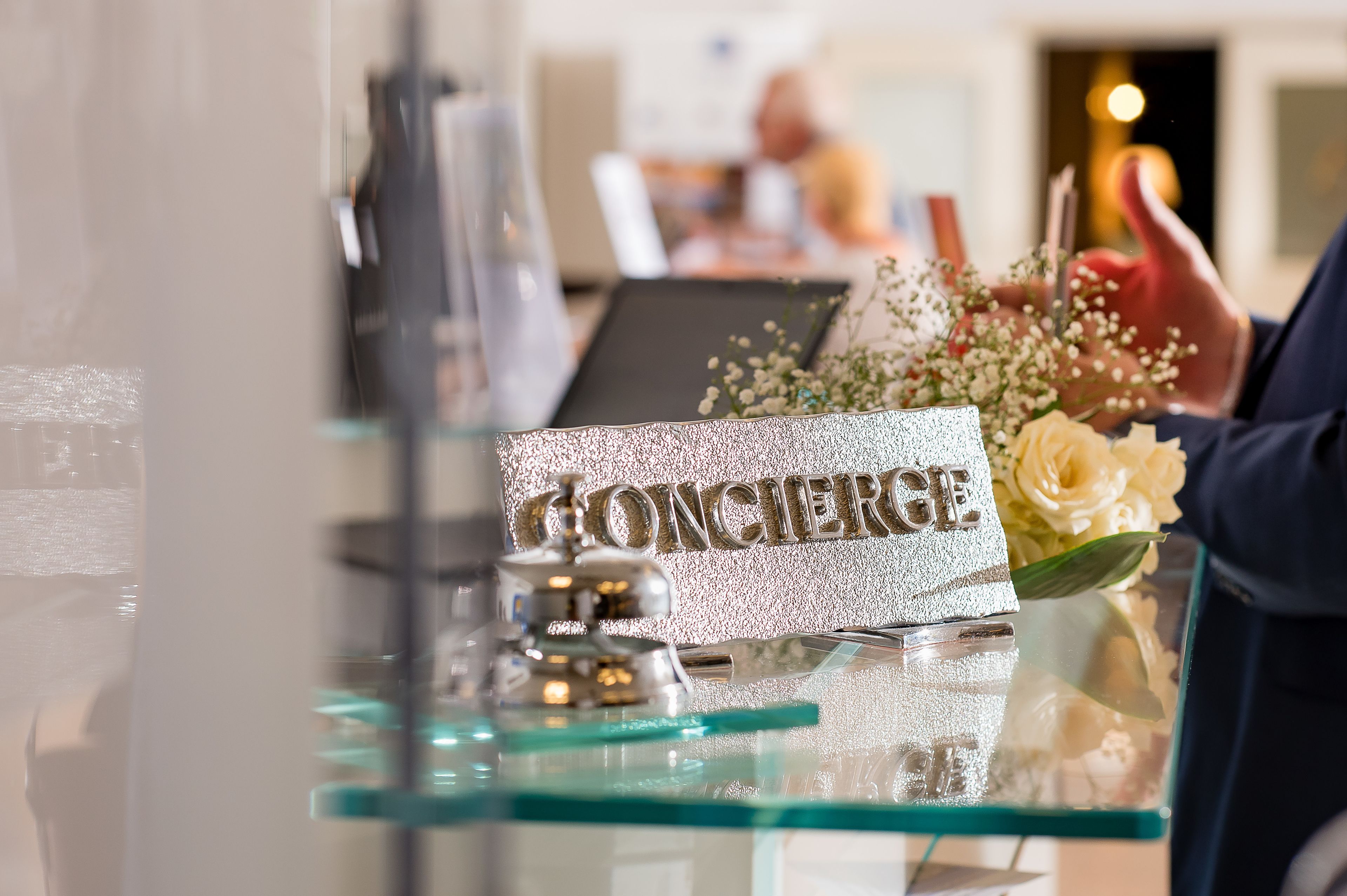 A reception desk with a sign reading "HONCIERGE" and a vase with flowers.