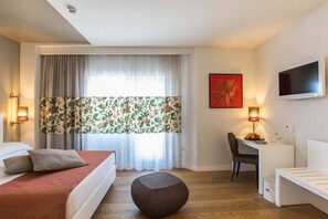 A hotel room with a bed, a desk, a chair, a television, and a window with curtains. - Hotel Caravel (Rome)