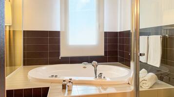 A modern bathroom with a freestanding bathtub, a large mirror, and a window providing natural light.