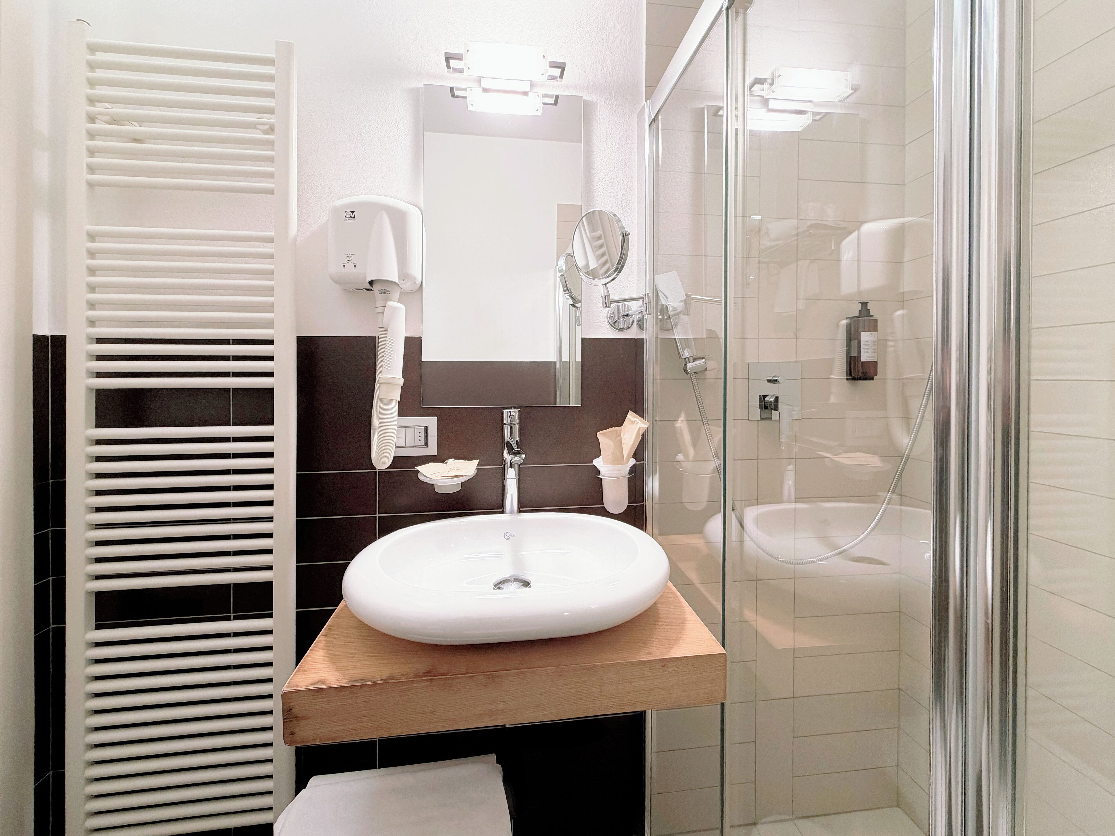 Une salle de bain moderne avec un lavabo blanc, un miroir et une cabine de douche en verre.