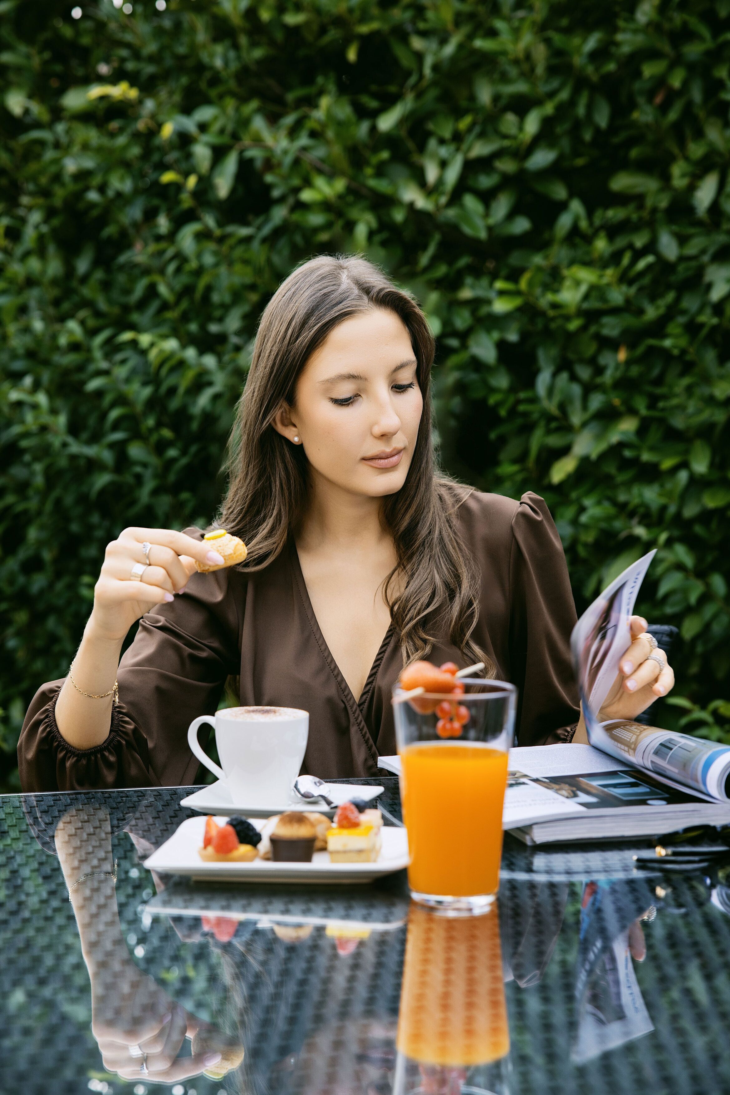 A person sitting at a table with a cup of coffee, a glass of orange juice, and a plate of pastries.