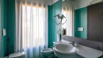 Ein Badezimmer mit Toilette, Bidet und einem großen Waschbecken mit Spiegel darüber.