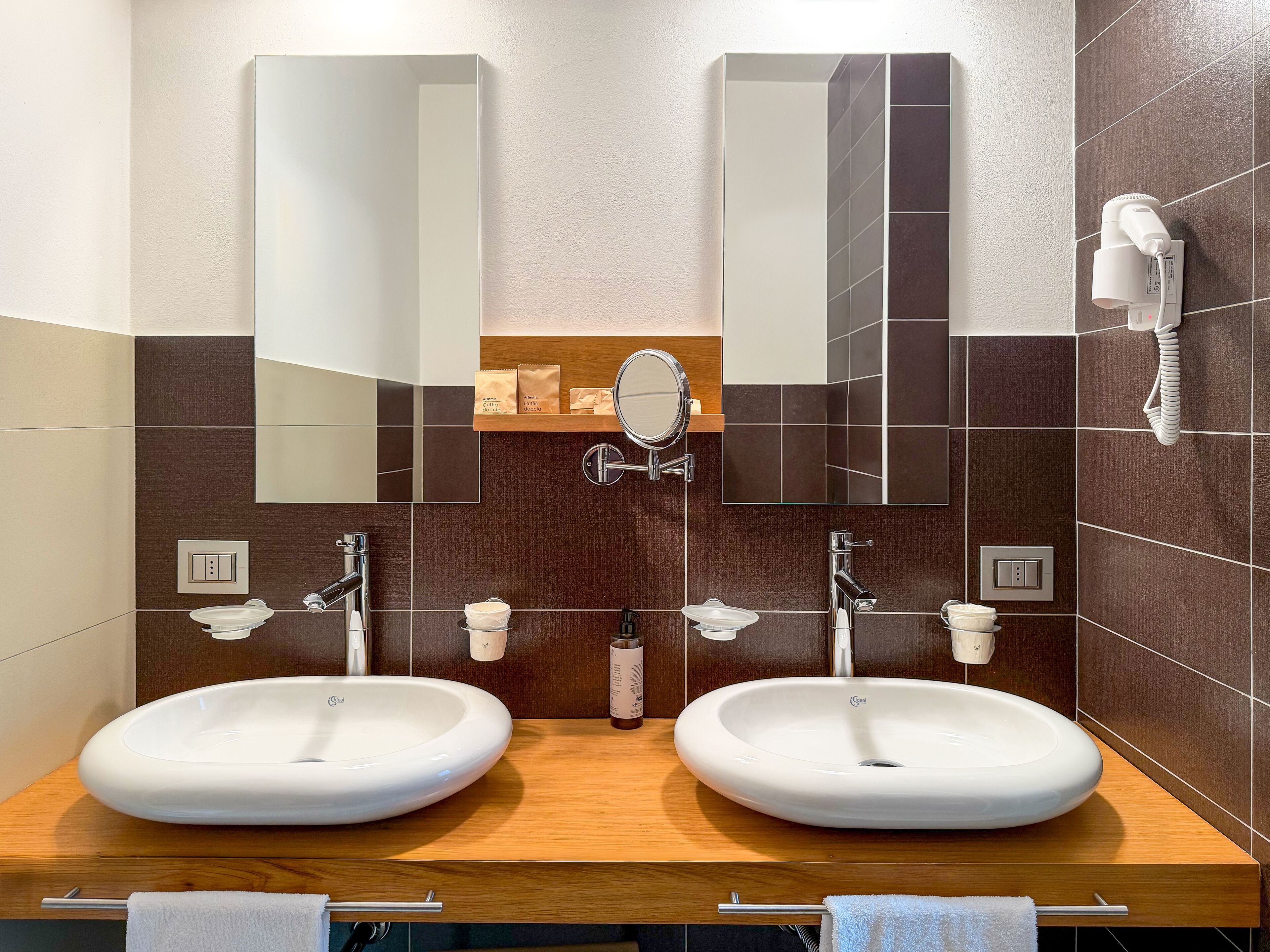 Ein modernes Badezimmer mit zwei Waschbecken, einem Spiegel und einem Handtuchhalter.