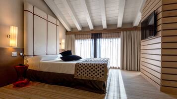 Quarto de hotel com uma cama, televisão na parede e janela com cortinas.