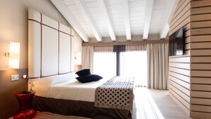 A hotel room with a bed, a red vase, a wall-mounted TV, and a window with curtains. - Hotel Filanda (Cittadella)