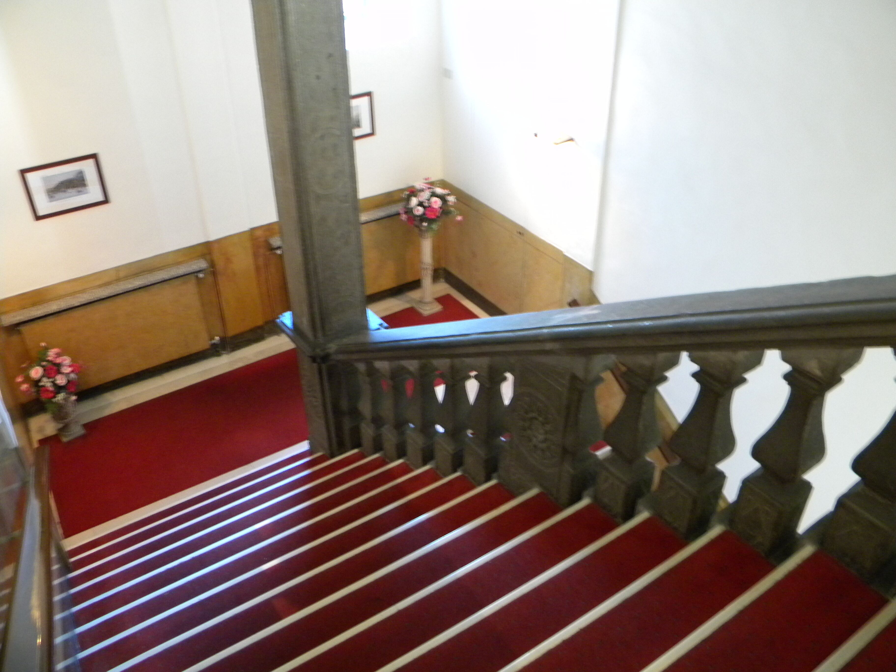 A staircase with red carpeted steps and wooden railings.