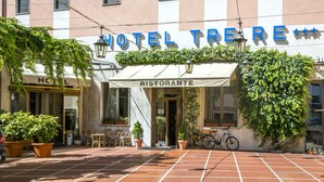 A hotel named "HOTEL TRE RE" with a restaurant sign, outdoor seating, and potted plants. - Albergo Ristorante Tre Re (Como)