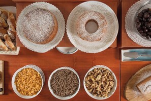 A table with various food items including pastries, a cake, and bowls of cereal and granola.
