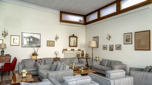 A spacious living room with grey upholstered sofas, a wooden coffee table, and a red chair. - Albergo Ristorante Tre Re (Como)