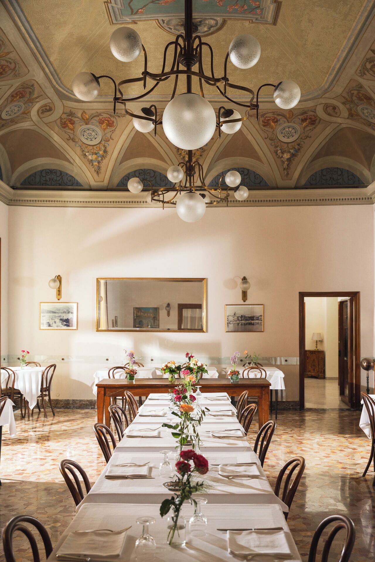 Comedor formal con una larga mesa dispuesta para una comida, una araña y un techo decorativo.