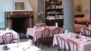 A dining area with tables set for service, a fireplace, and a bookshelf. - Albergo Ristorante Tre Re (Como)